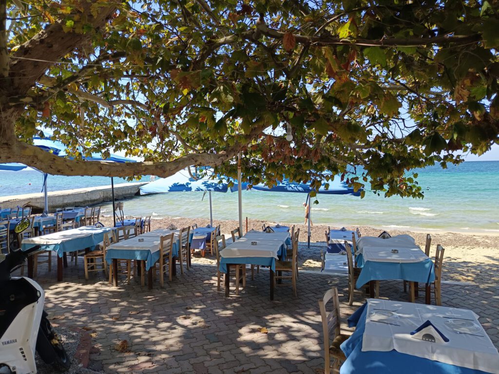 Tische an einer griechischen Strandtaverne direkt am Meer